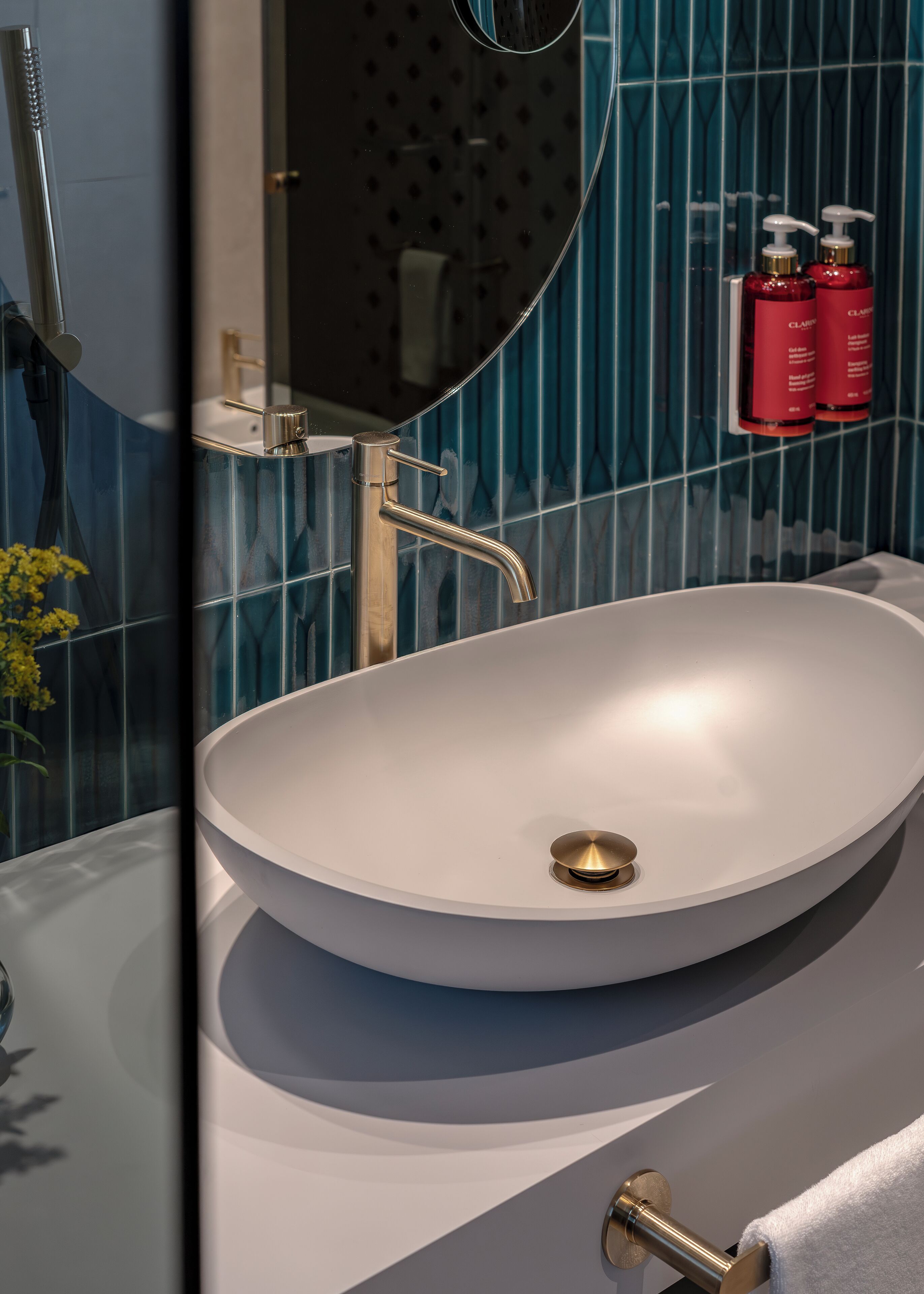 Ein modernes Badezimmer mit einem runden Waschbecken, einer Handbrause und einem Handtuchhalter.