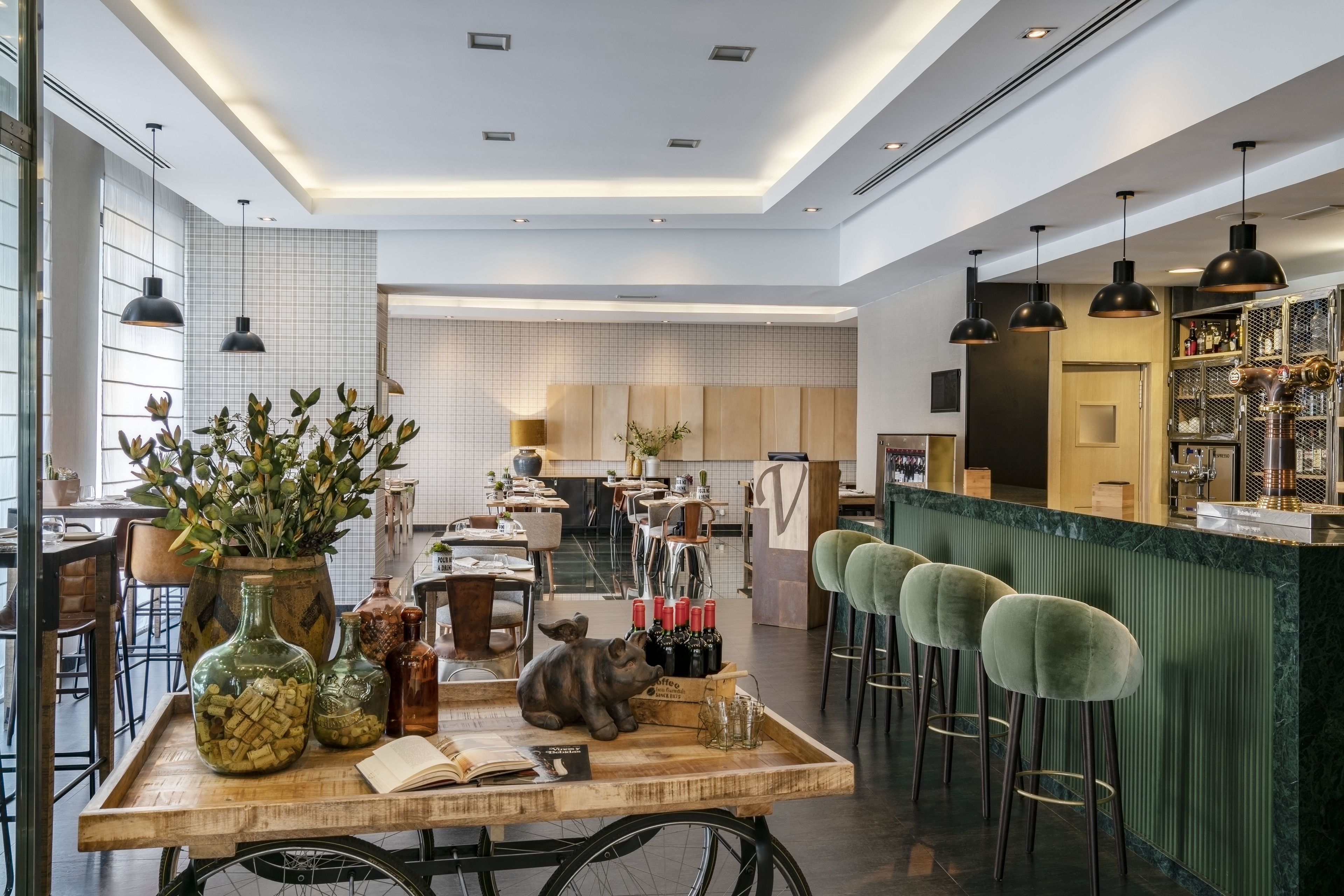 Un interior moderno con una mesa de madera, taburetes de bar y una zona de bar.