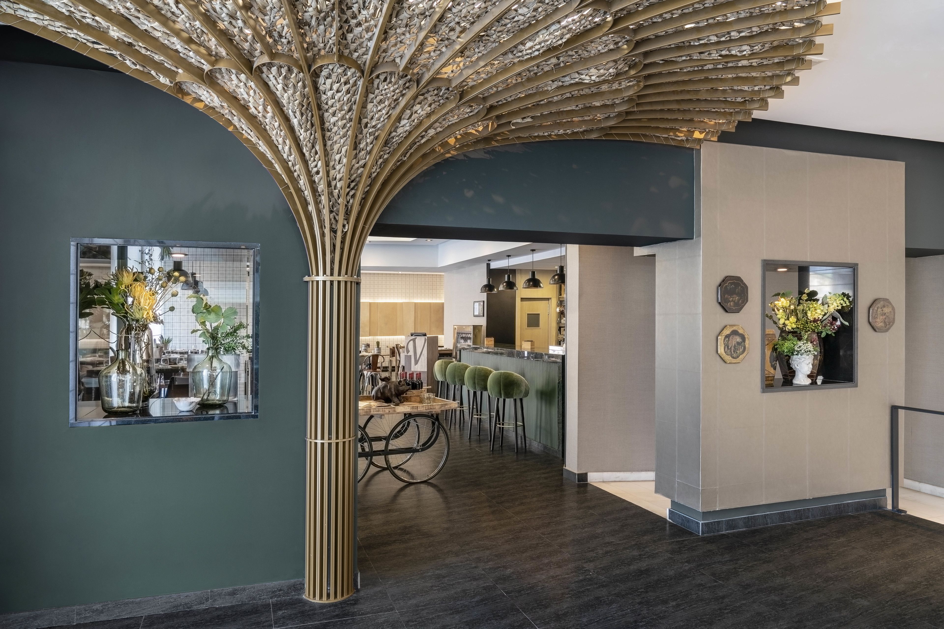 Un interior moderno con un diseño de techo único, una zona de bar y un espacio de estar con una mesa y sillas.
