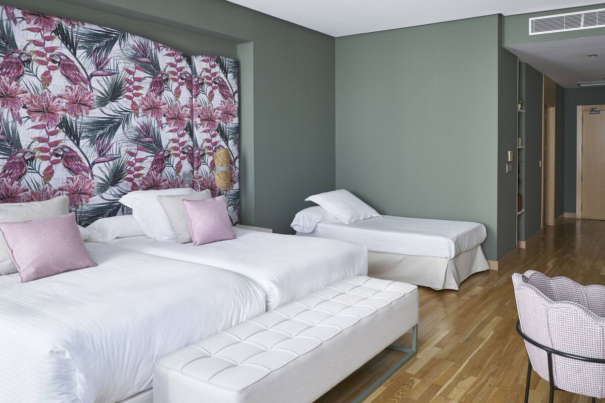 A hotel room with two single beds, a large bed, and a sofa bed.