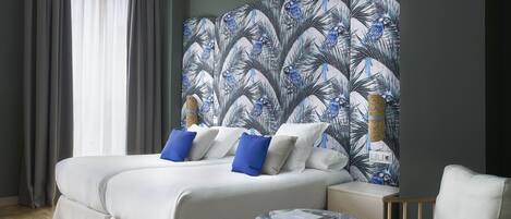 A modern hotel room with a large bed, two pillows, a small round table, and a chair.