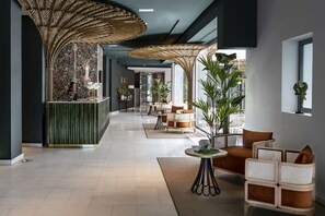 Un moderno vestíbulo de hotel con mostrador de recepción, zona de estar y amplios ventanales.