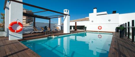 A pool area with a wooden deck, lounge chairs, and a lifebuoy.