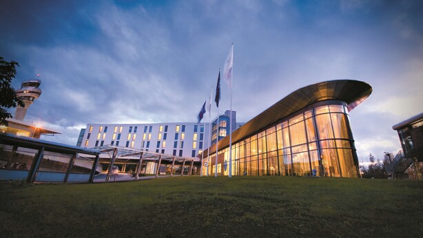 A modern hotel with a curved glass facade, a control tower, and flags. - Radisson Blu Hotel, Trondheim Airport (Stjordal)