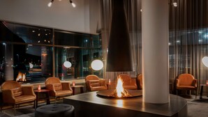A modern lounge area with leather chairs, a central fire feature, and large windows offering a city view. - Radisson Blu Hotel, Trondheim Airport (Stjordal)