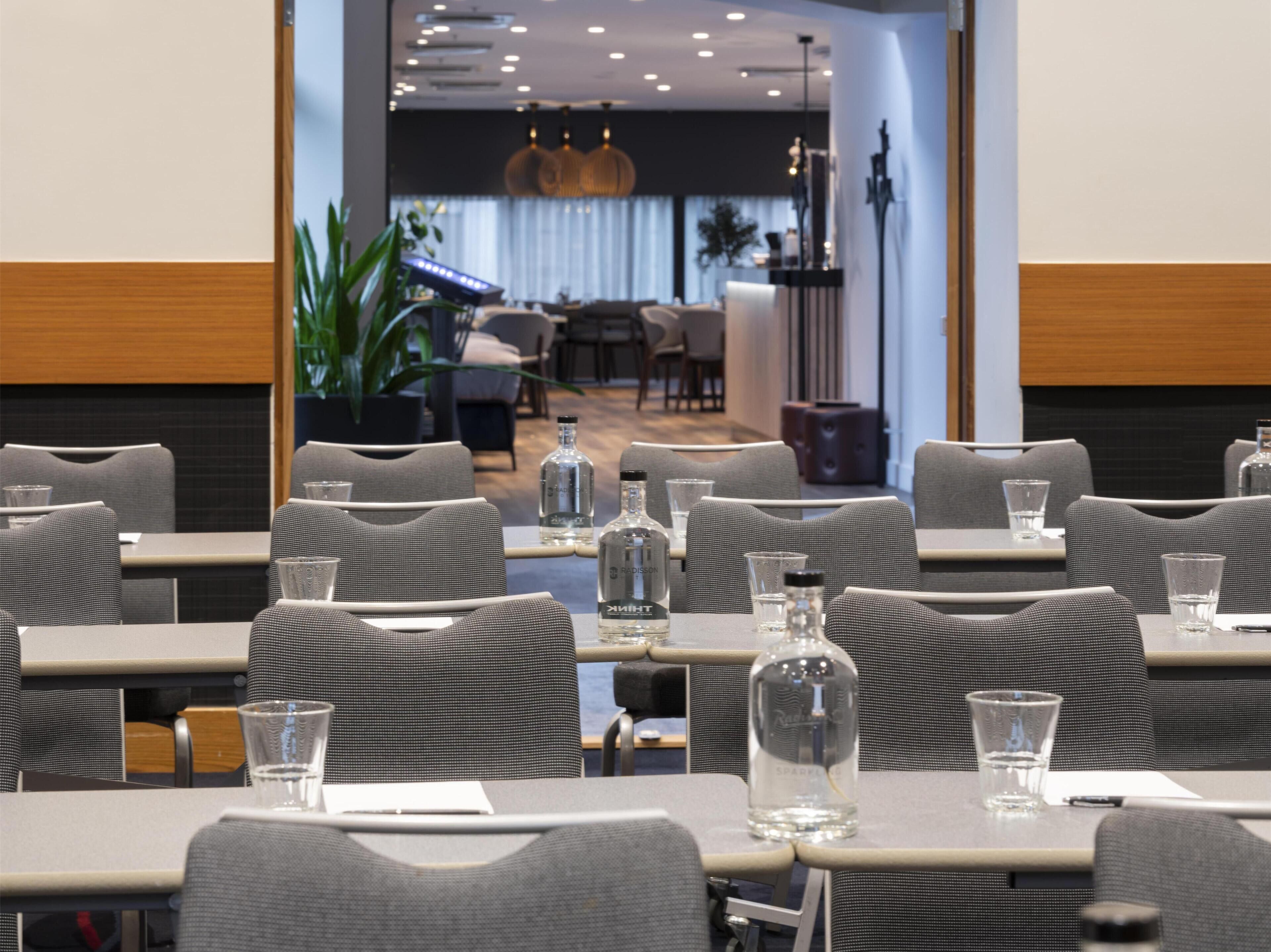 A restaurant with tables set for dining, chairs, and a bar area in the background.