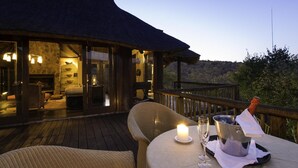 An outdoor dining area with a table set for two, a candle, and a champagne bottle. - Tshwene Lodge (Vaalwater)