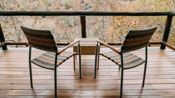 A wooden deck with two wicker chairs and a small table.