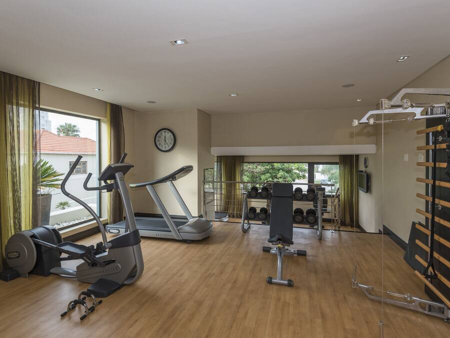 Un gimnasio con cintas de correr, elípticas y una estructura para pesas.