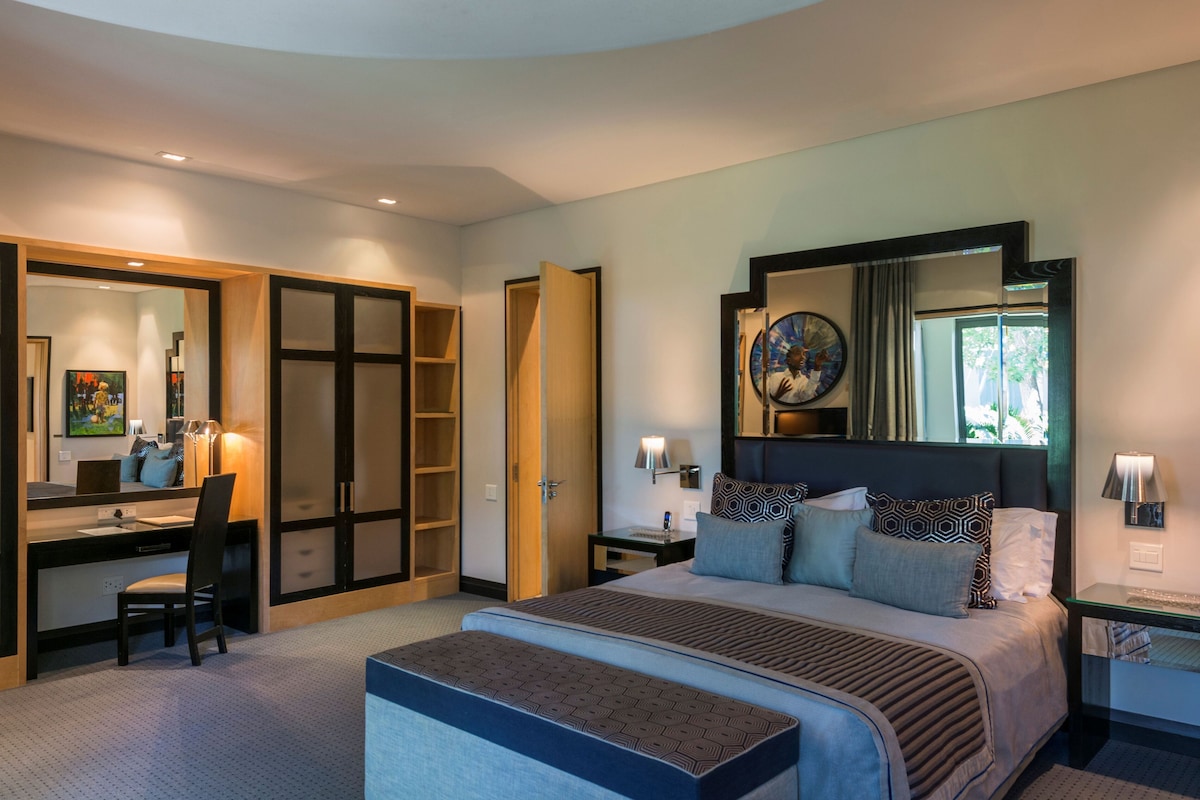 Una habitación de hotel moderna con una cama grande, un escritorio y un vestidor.