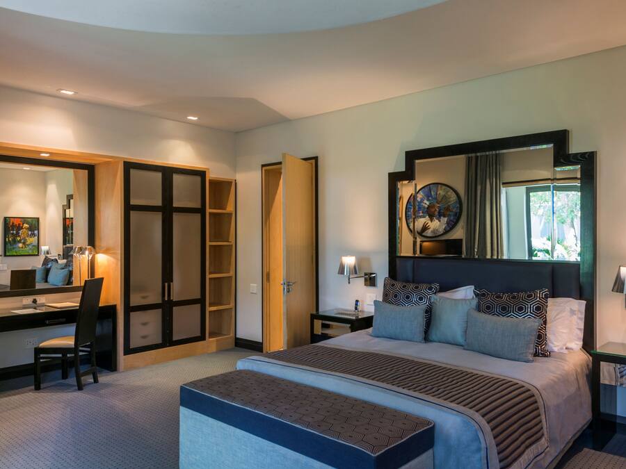 A modern hotel room with a large bed, a desk, and a walk-in closet.