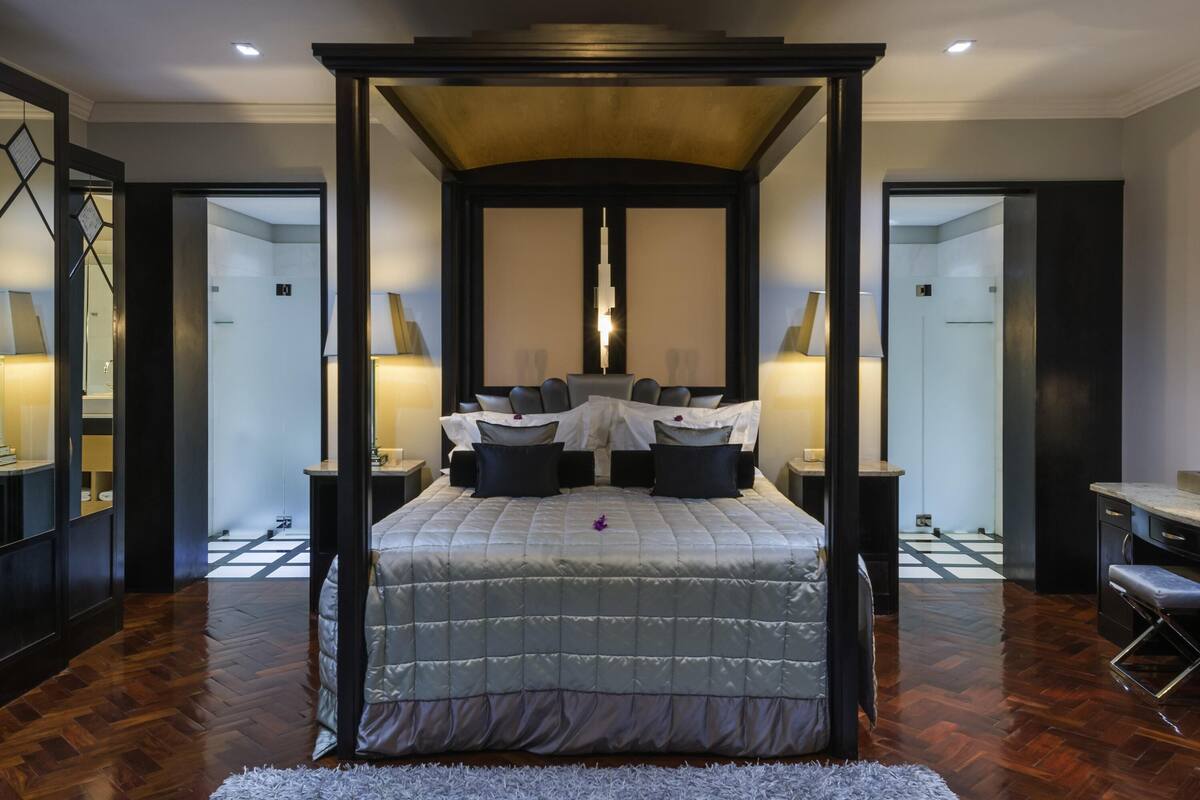 A bedroom with a four-poster bed, a large mirror, and a checkered floor.
