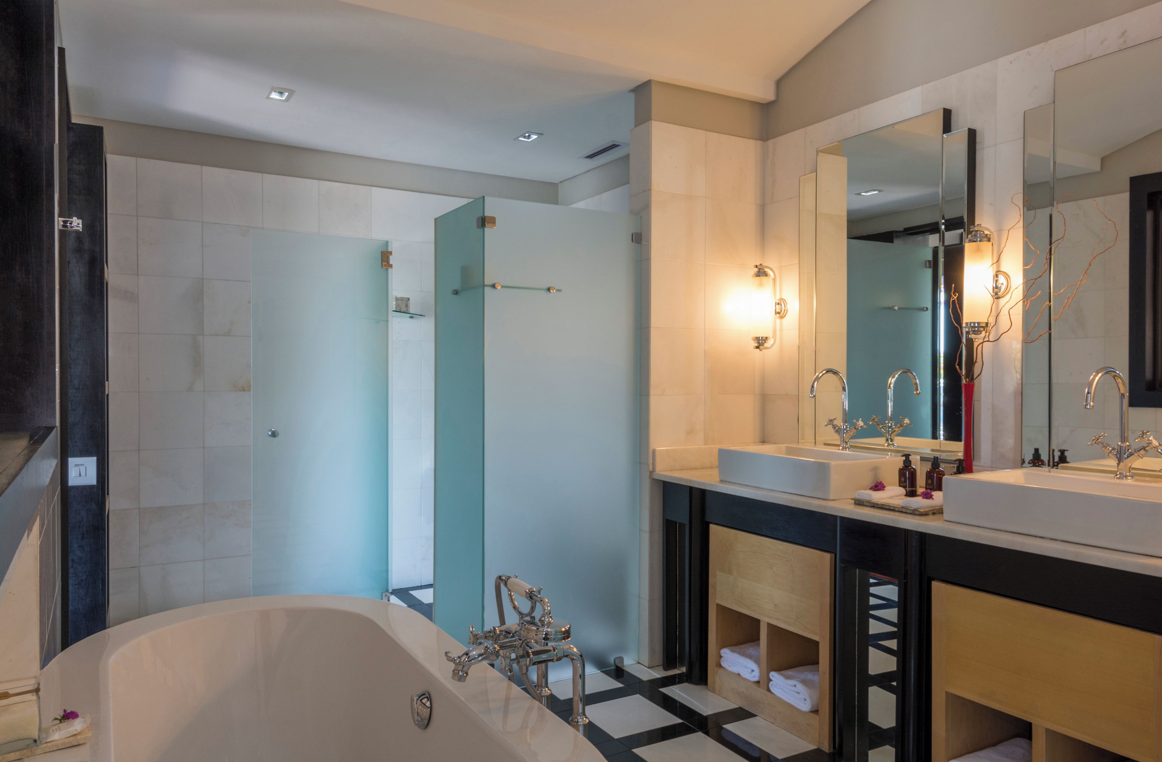 A modern bathroom with a bathtub, two sinks, and a large mirror.