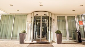 A hotel entrance with a revolving door, glass doors, and potted plants. - Aparthotel Adagio Grenoble Centre (Grenoble)