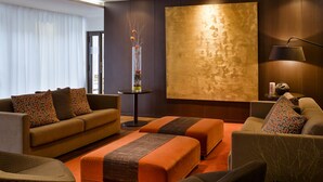 A modern hotel room with a sofa, ottoman, and armchair, a large abstract painting on the wall, and a floor lamp. - Aparthotel Adagio Grenoble Centre (Grenoble)