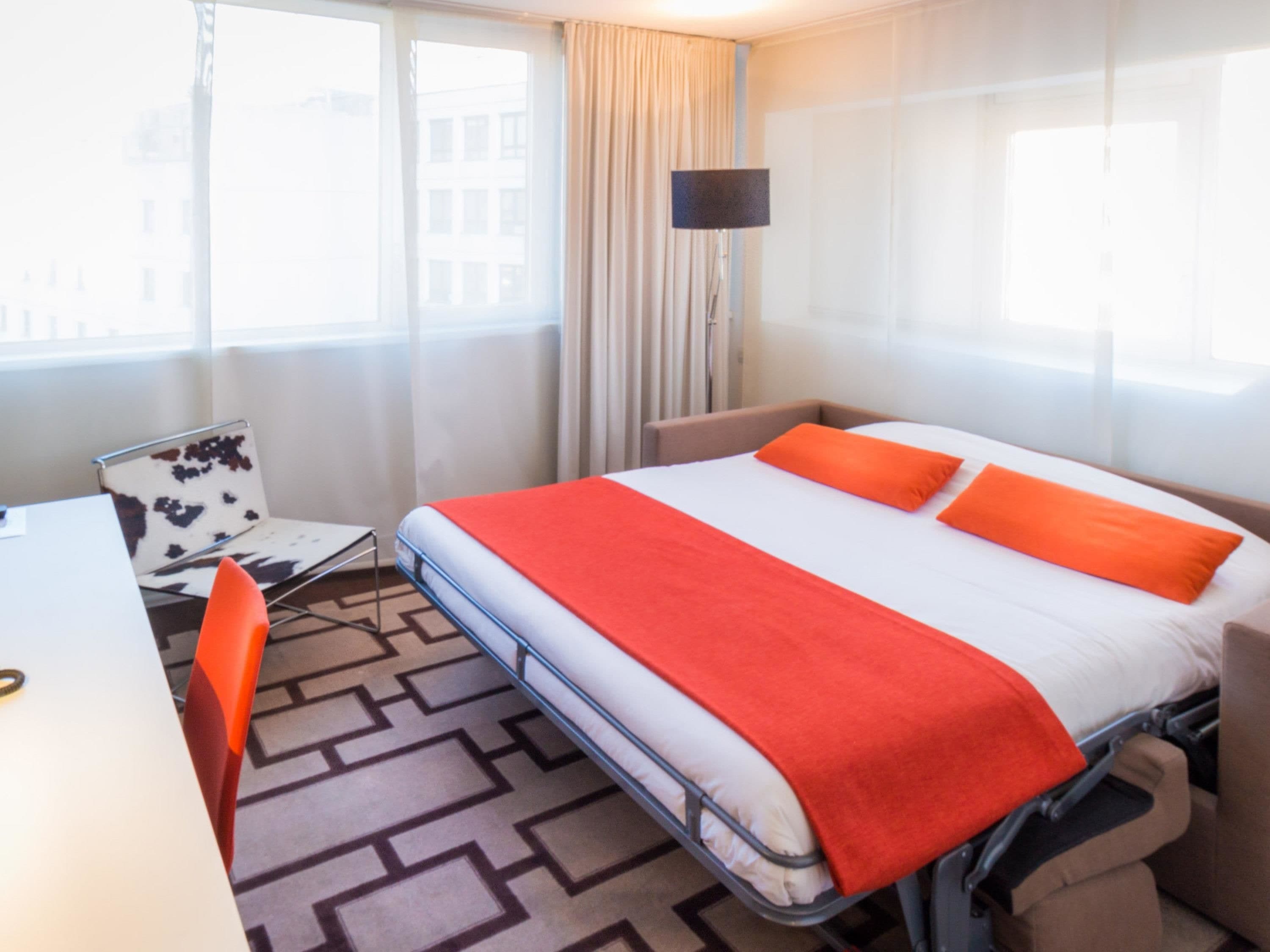 Una habitación de hotel con una cama, un escritorio y una silla.