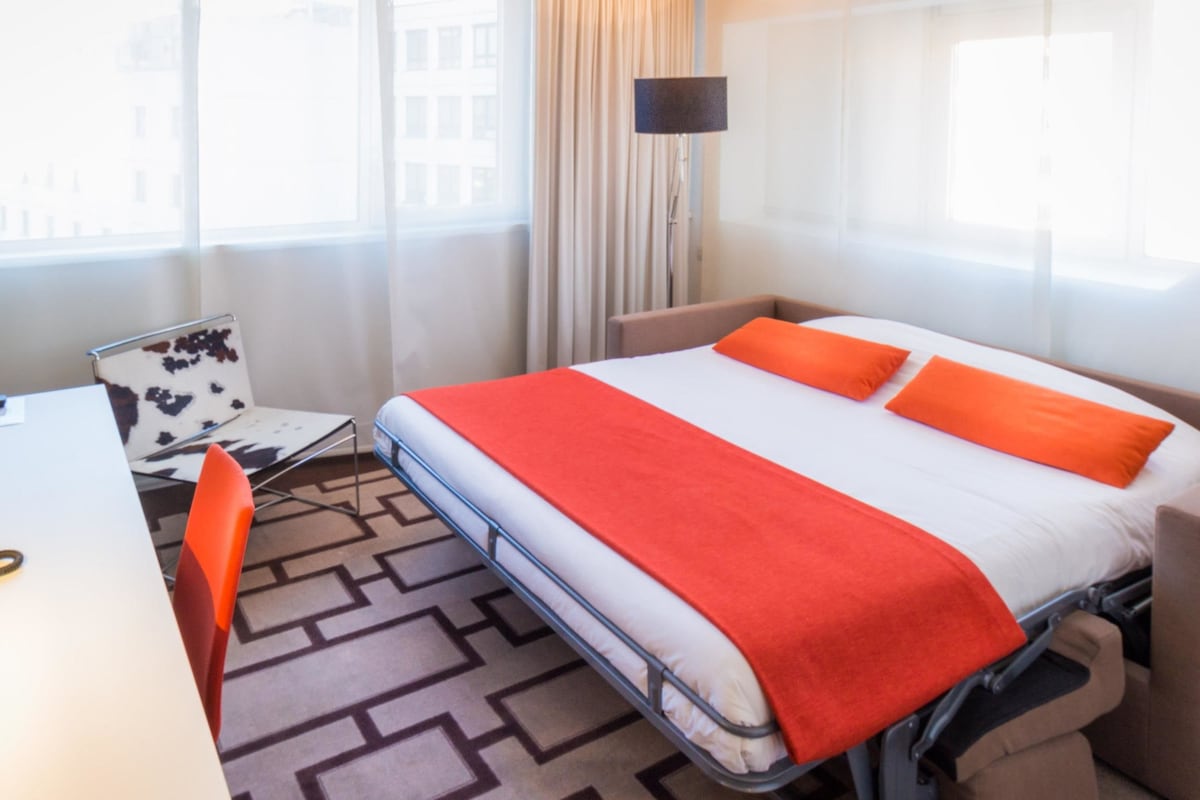 Een hotelkamer met een bed, een bureau en een stoel.