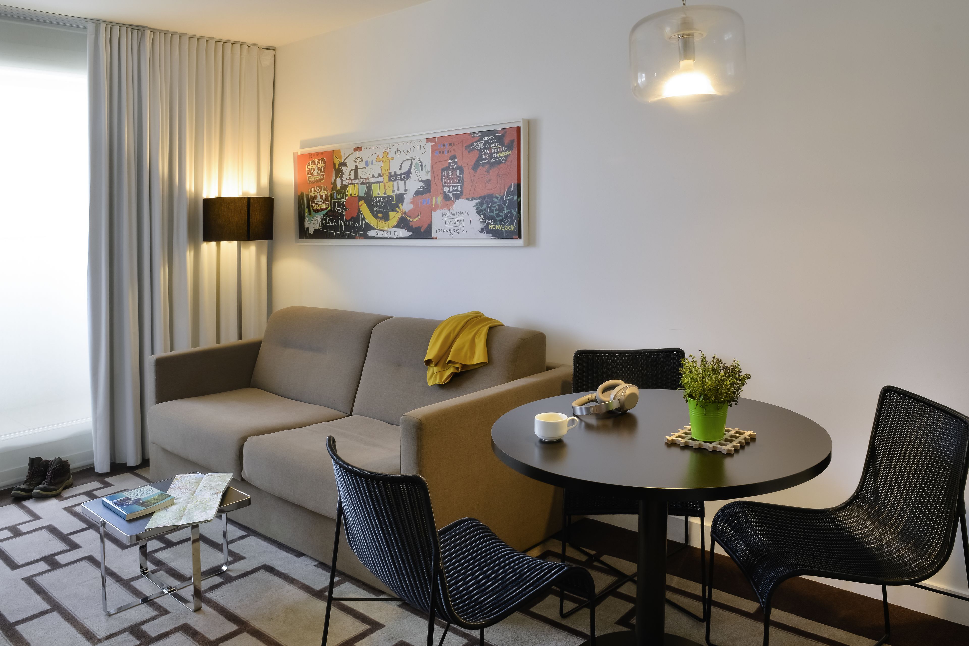 A modern living room with a sofa, two chairs, a coffee table, and a lamp.