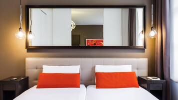 Habitación de hotel con dos camas, un espejo grande y lámparas colgantes.