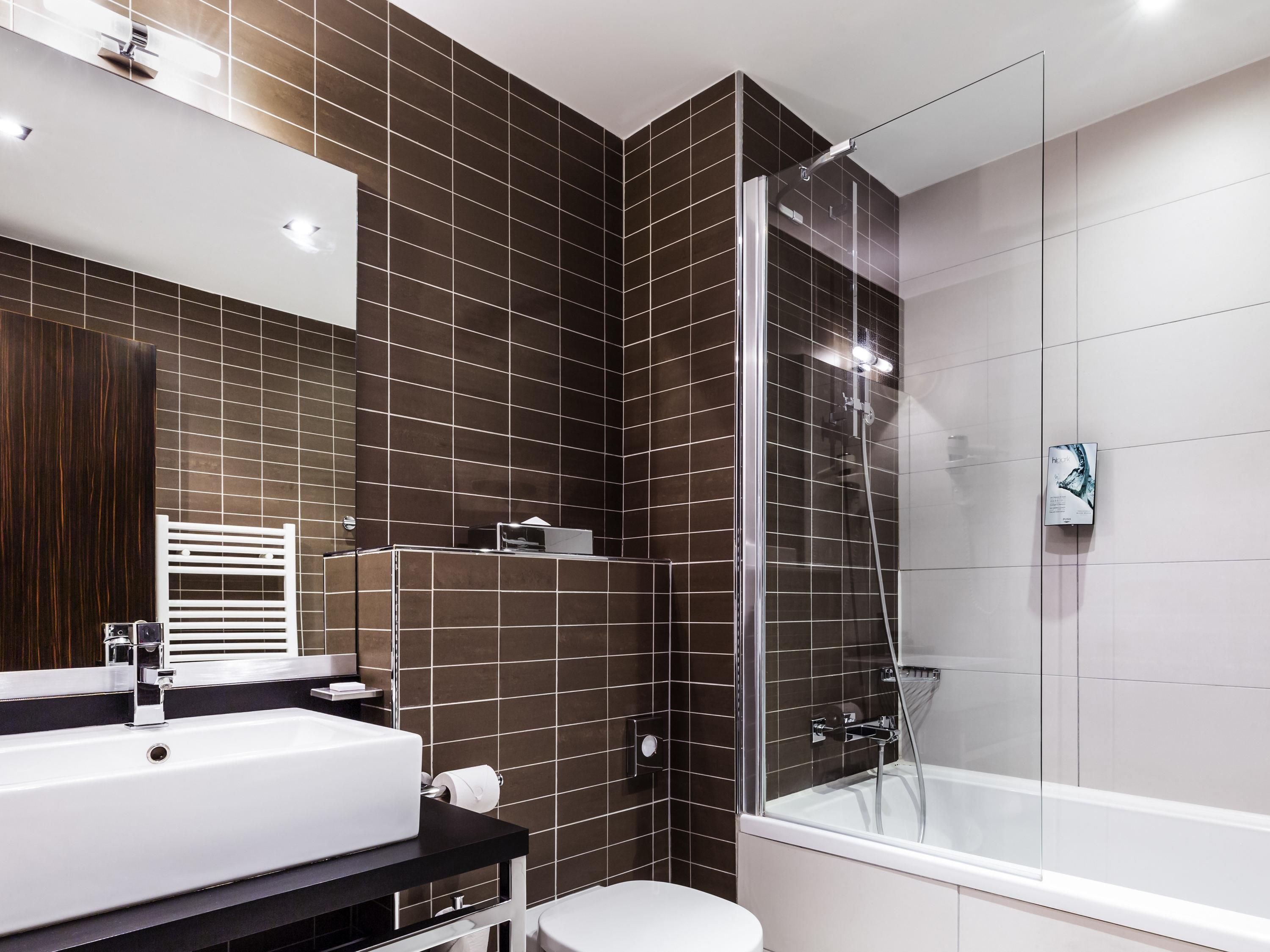 A modern bathroom with a glass-enclosed shower, a white bathtub, and a large white sink.