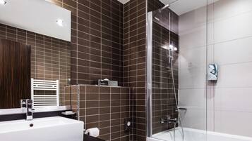 A modern bathroom with a glass-enclosed shower, a white bathtub, and a large white sink.