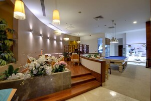 Un vestíbulo moderno con mesa de billar, zona de estar y plantas decorativas.