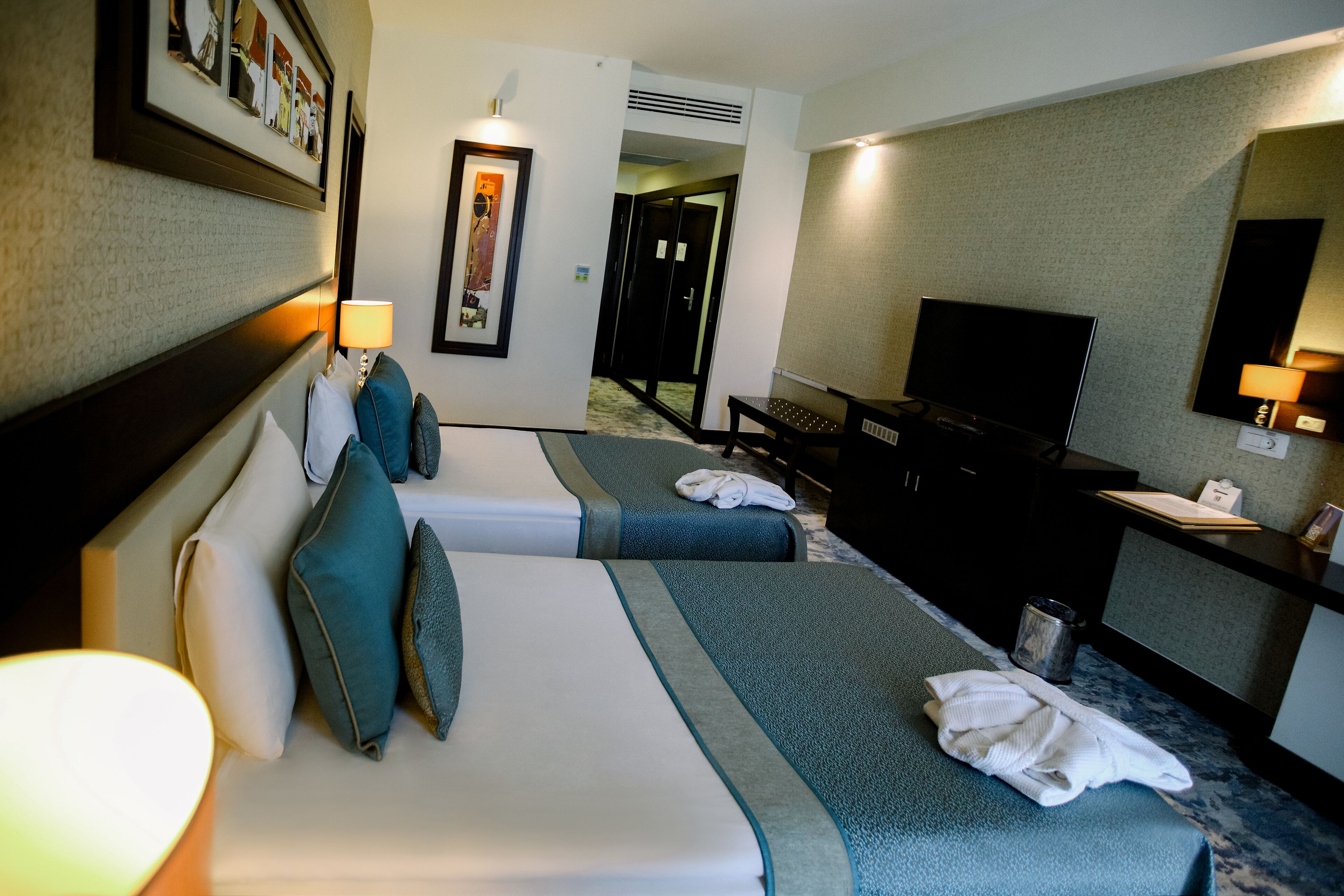 Une chambre d’hôtel avec deux lits, un bureau, une télévision et un miroir.