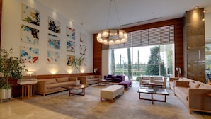 A spacious living room with a large window, multiple sofas, and abstract art on the walls. - Baia Bursa Hotel (Bursa)