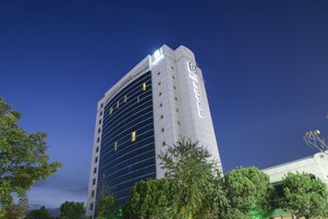 Un hotel alto con un diseño moderno, que destaca un llamativo letrero con la palabra 'HOTEL' en la fachada.