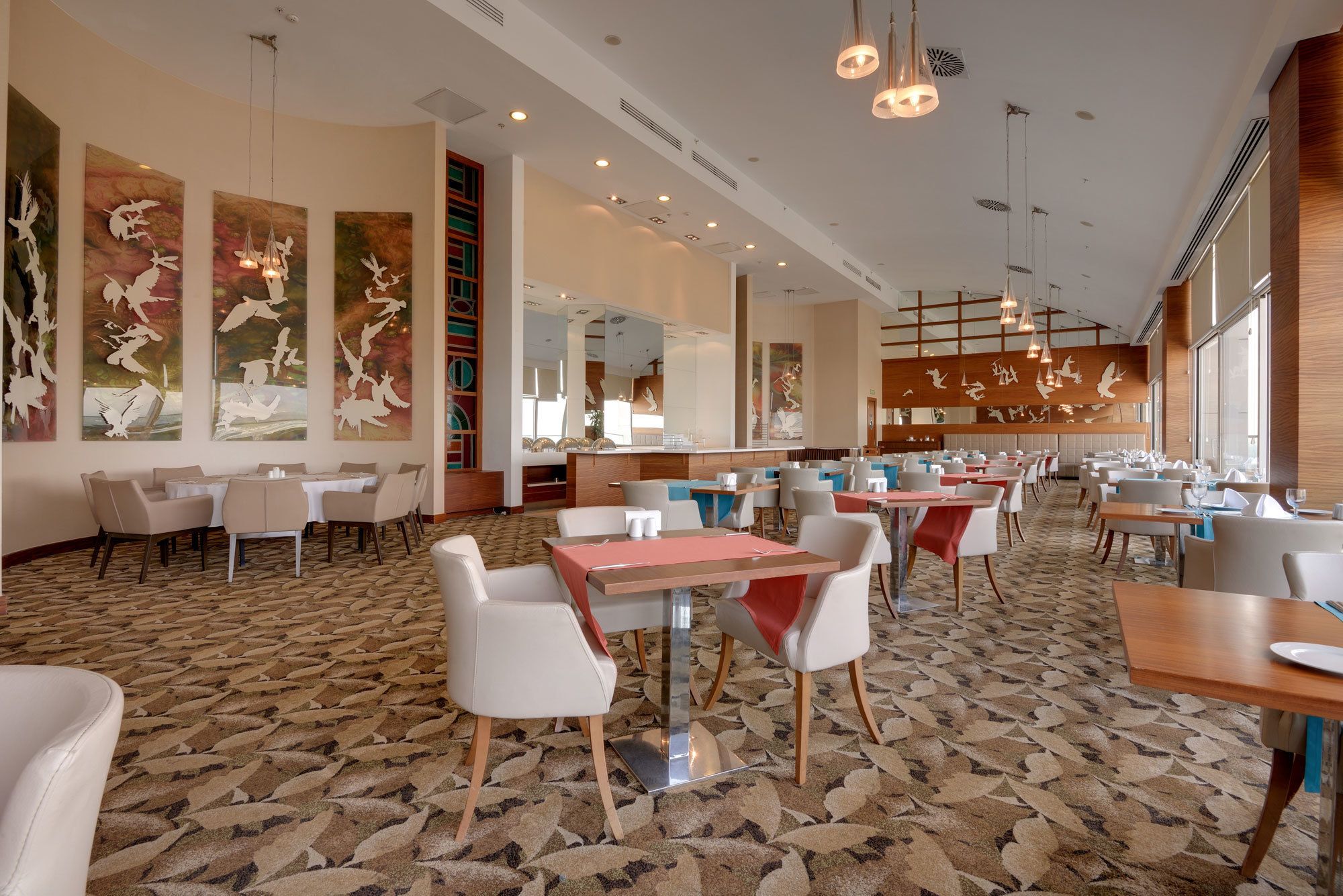 Un restaurante espacioso con techos altos, iluminación moderna y obras de arte en las paredes.