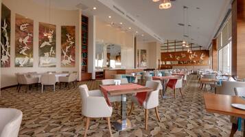 Un restaurante espacioso con techos altos, iluminación moderna y obras de arte en las paredes.