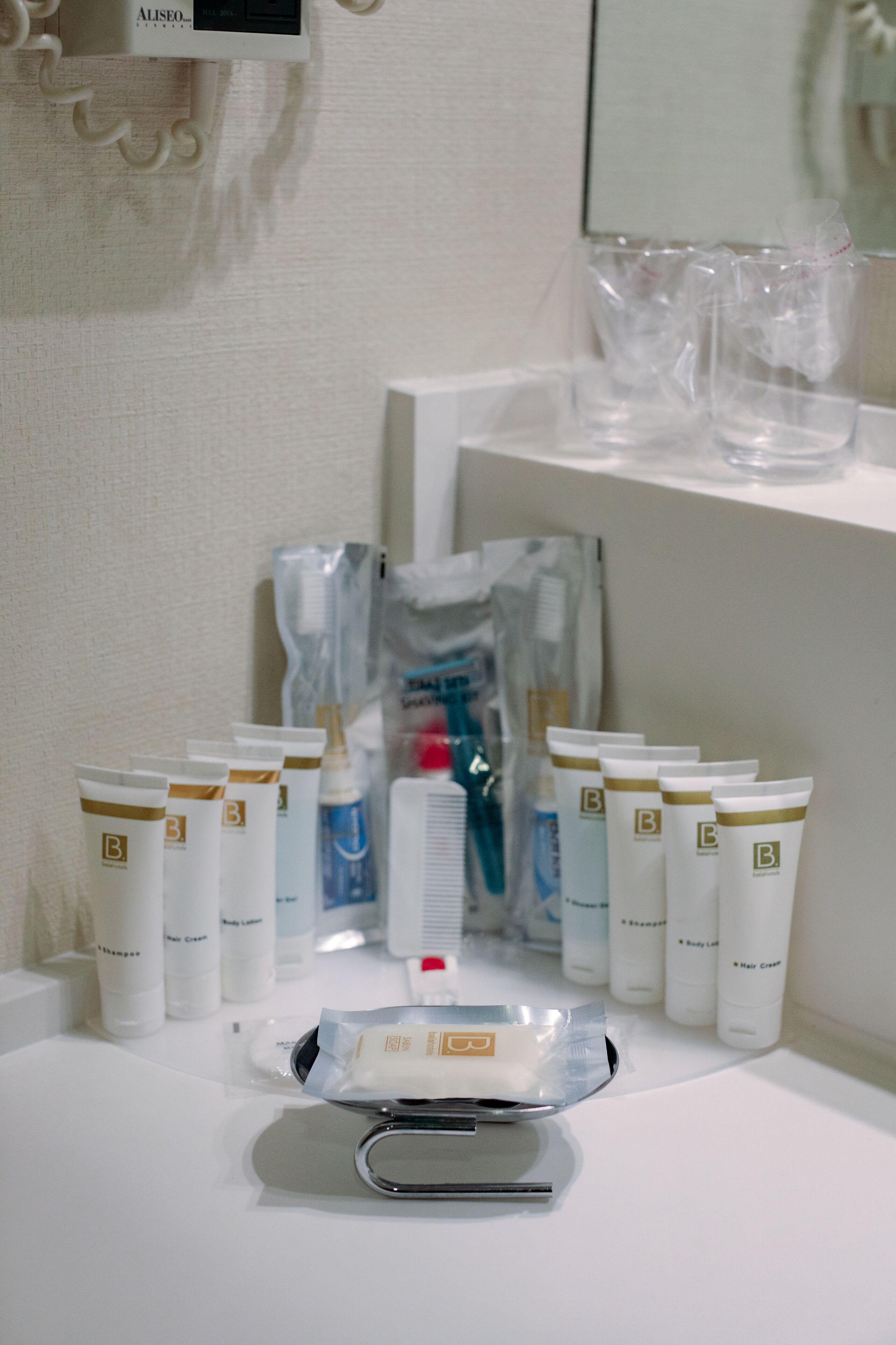 A display of various toiletries including body lotion, shampoo, and conditioner on a white counter.