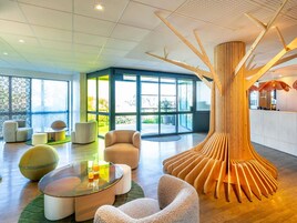 Un hall d’entrée moderne doté d’une structure en bois originale, de sièges confortables et de grandes fenêtres offrant une vue sur l’extérieur.