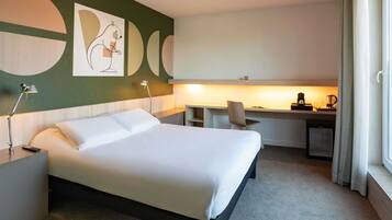 A hotel room with a large bed, a desk, and a chair.