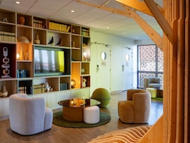 Un salon moderne doté d’un grand téléviseur à écran plat, de bibliothèques et de sièges confortables.