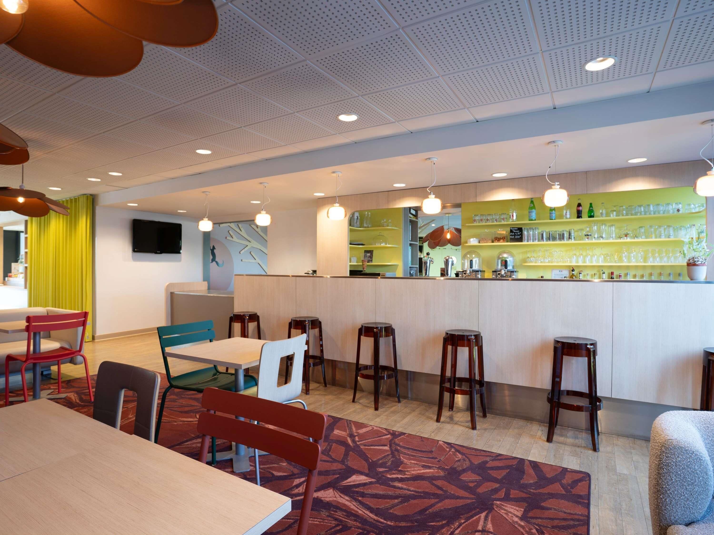A modern cafe with a bar area, seating arrangements, and a television screen.