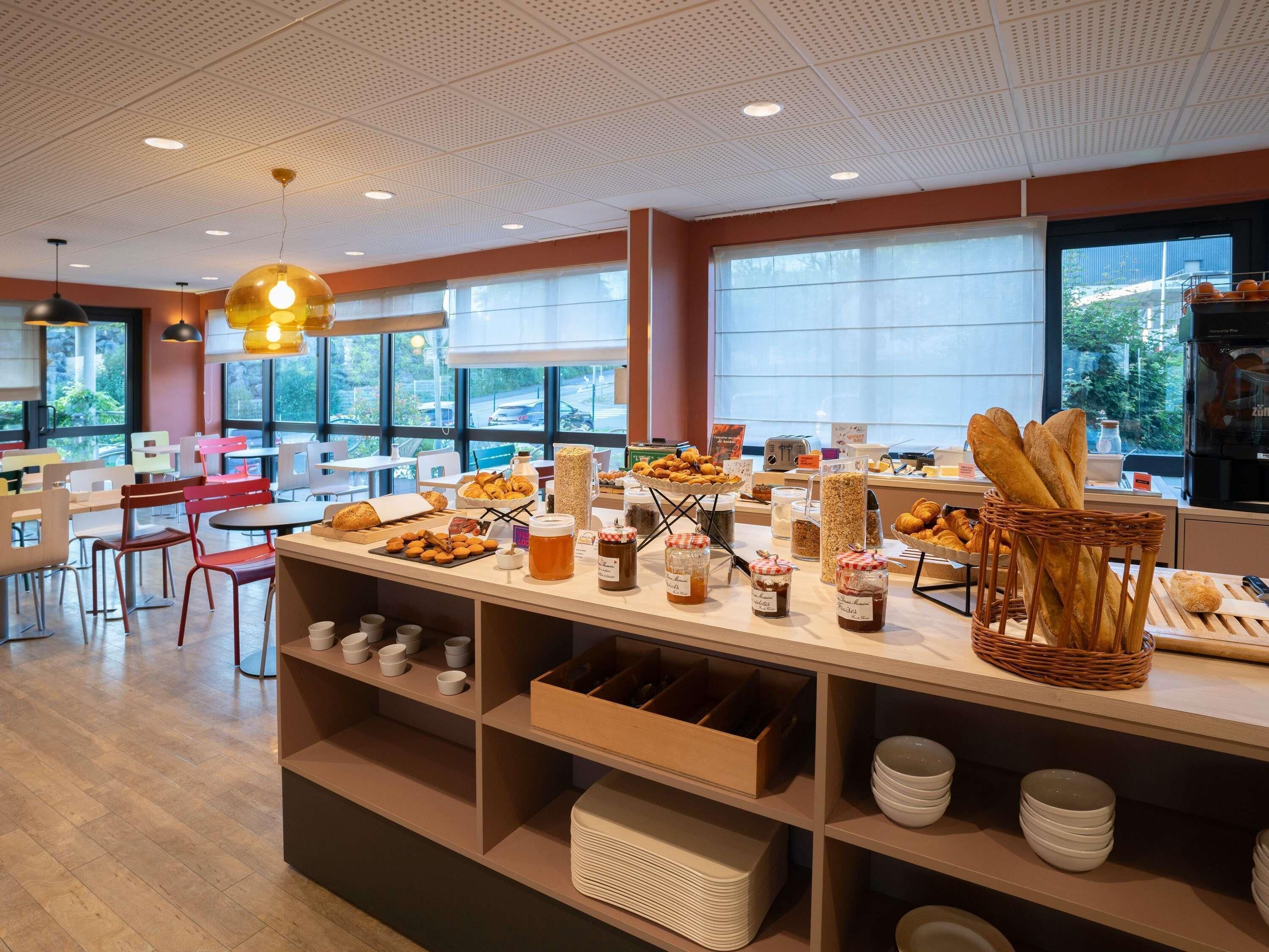 Buffet de l'esmorzar amb diversos aliments i zona de seients amb cadires i taules.