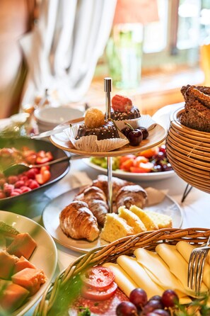 Ein Buffet mit verschiedenen Speisen, darunter Gebäck, Früchte und Käse.