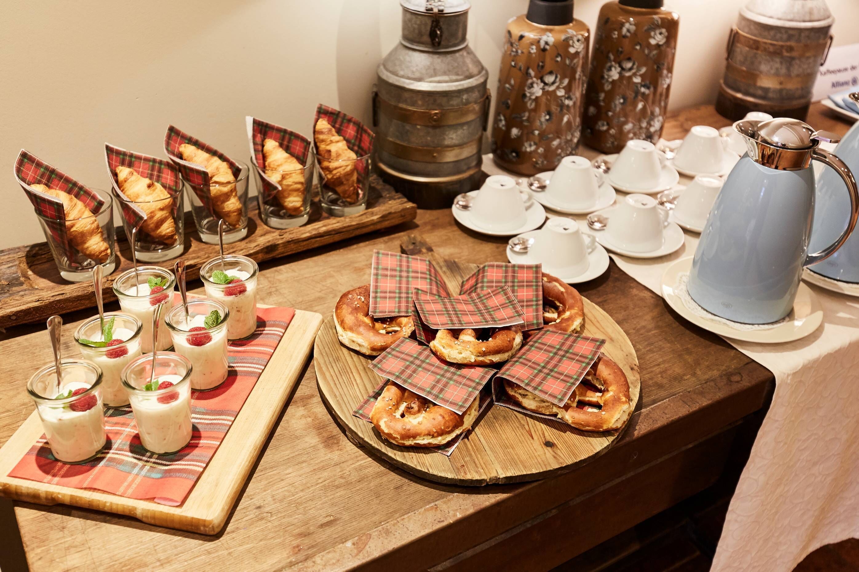 A buffet table with pastries, glasses of beverages, and tea service.