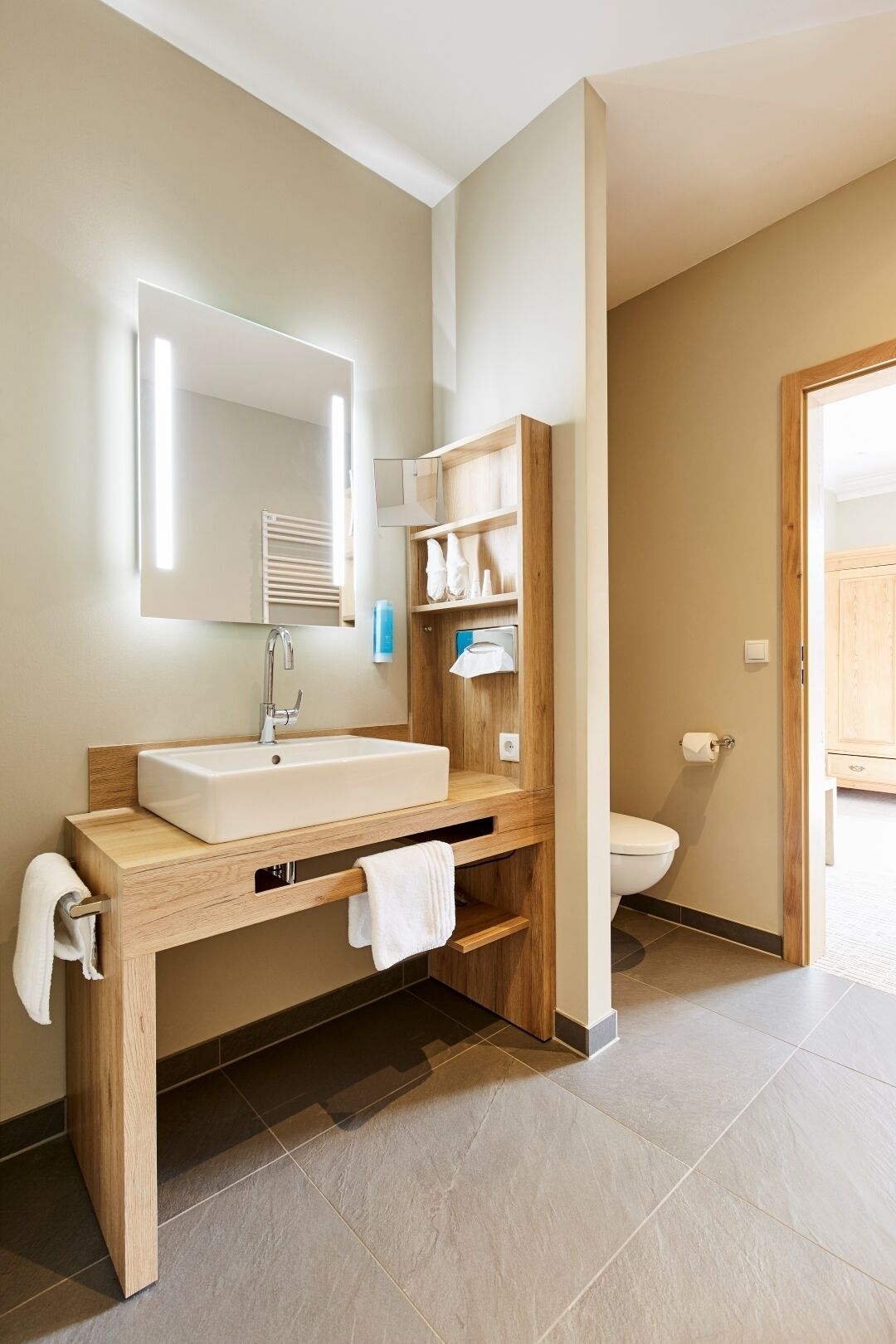 Une salle de bain moderne avec un meuble-lavabo en bois, un grand miroir et des toilettes.