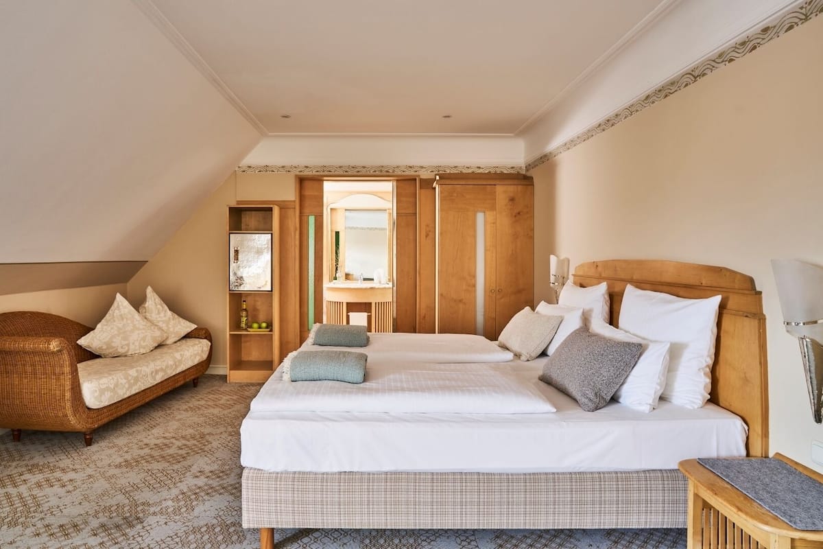 A bedroom with a large bed, a sofa, and a wooden wardrobe.
