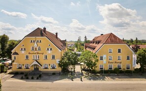 Un bâtiment jaune portant les enseignes « Gasthof Stangl » et « Hôtel Stangl ». Il présente un style architectural européen traditionnel, avec un toit à forte pente et de nombreuses fenêtres.