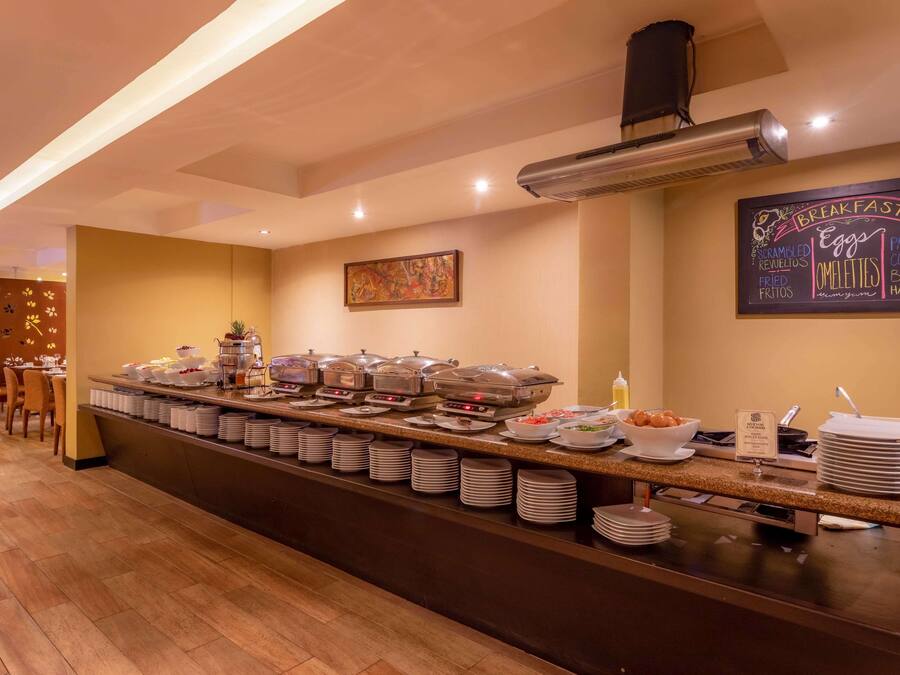 Un área de desayuno tipo buffet con diversas opciones de comida, como huevos revueltos, tortillas y huevos cocidos.