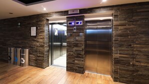 An elevator with a stone wall design, a trash bin, and a sign indicating the exit. - Sonesta Hotel Cusco (Cusco)