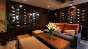 A modern interior with a seating area, wooden tables, and a wine rack with bottles. - Sonesta Hotel Cusco (Cusco)
