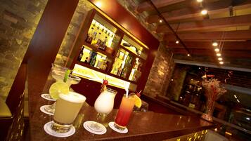 Un espace bar doté d’un comptoir en granit, de tabourets de bar et d’une variété de bouteilles et de verres.