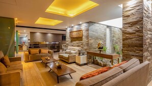 A modern living room with sofas, a coffee table, and a stone accent wall. - Sonesta Hotel Cusco (Cusco)