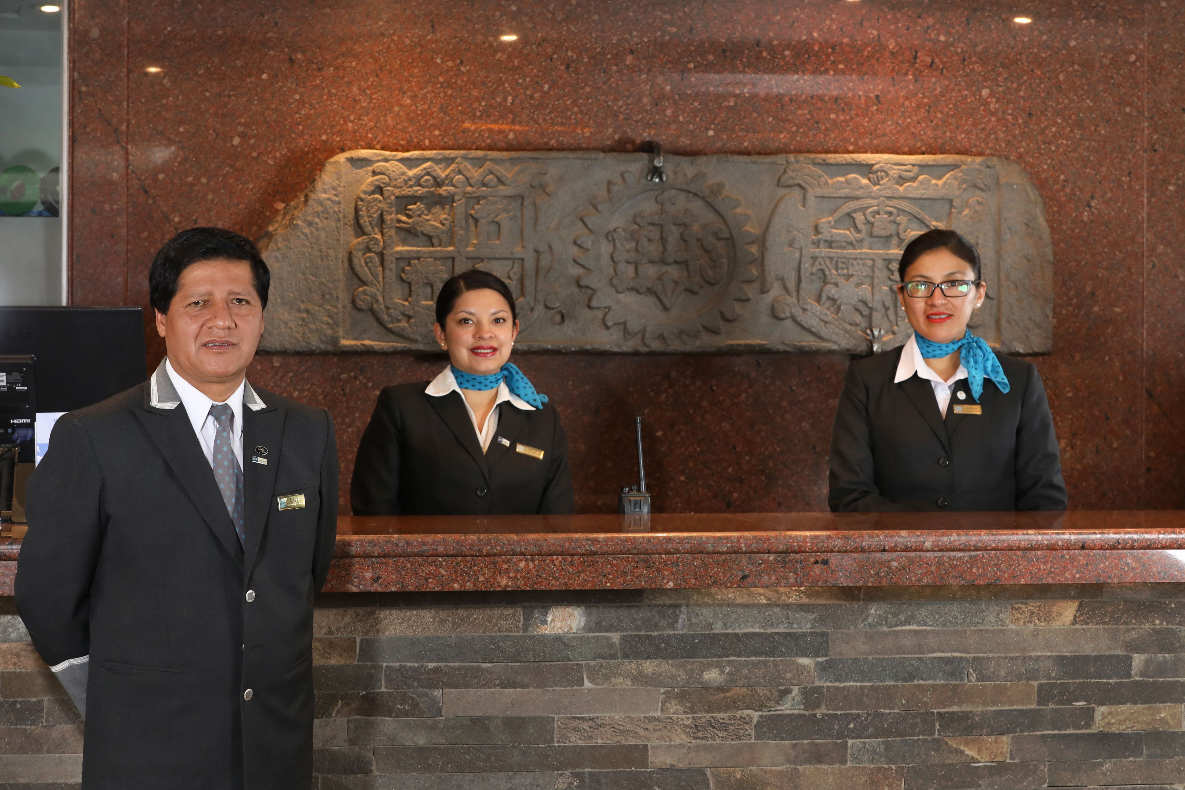 A reception desk with a stone wall and a carved emblem.