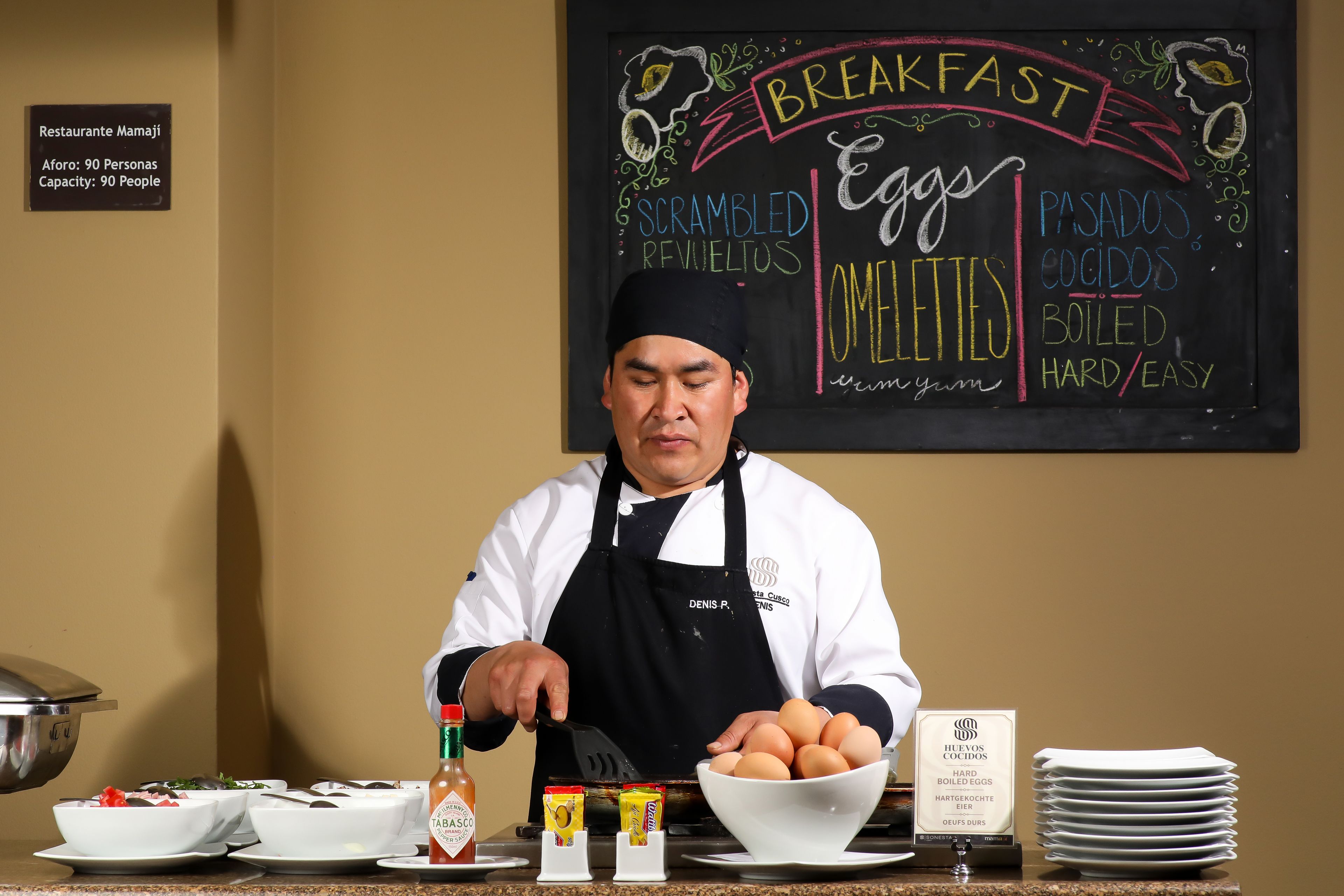 A breakfast buffet setup with scrambled eggs, omelets, and various condiments.
