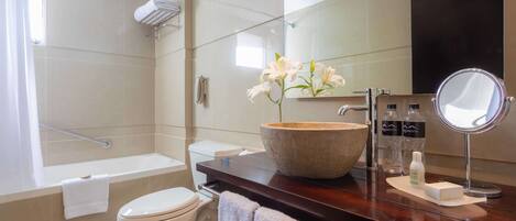 Un baño moderno con bañera, inodoro y tocador con un espejo grande y artículos de aseo.
